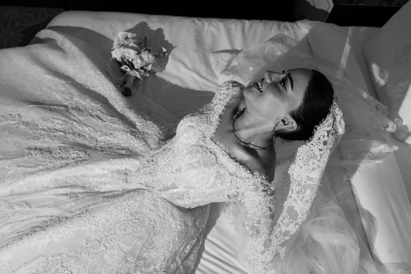 Kimya laughing on the bed in her lace gown and veil at the Four Seasons Hotel Baku, in black and white