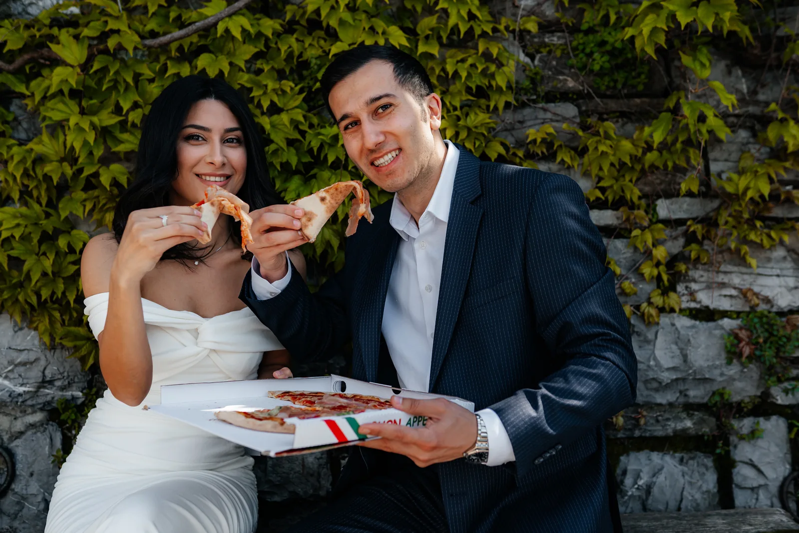 Ali ve Zariyat, Como Gölü'ndeki nişan çekimlerinde sarmaşıklı bir duvarın önünde pizzayla gülümsüyor