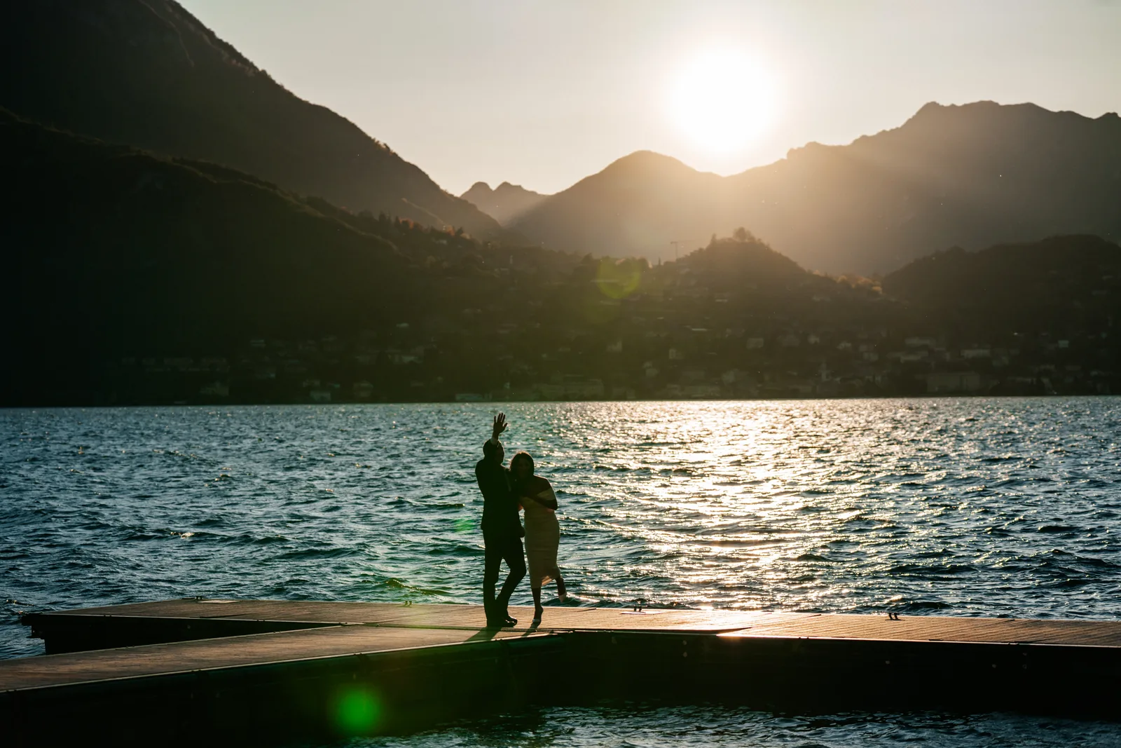 Two silhouettes celebrating on a lake pontoon at sunset