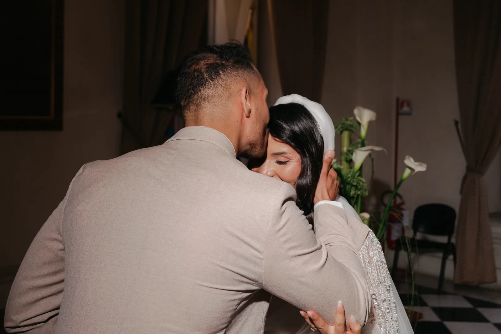 Mohammed kisses Hejrat on the forehead during their civil ceremony at the town hall as she holds his face, white calla lilies behind them