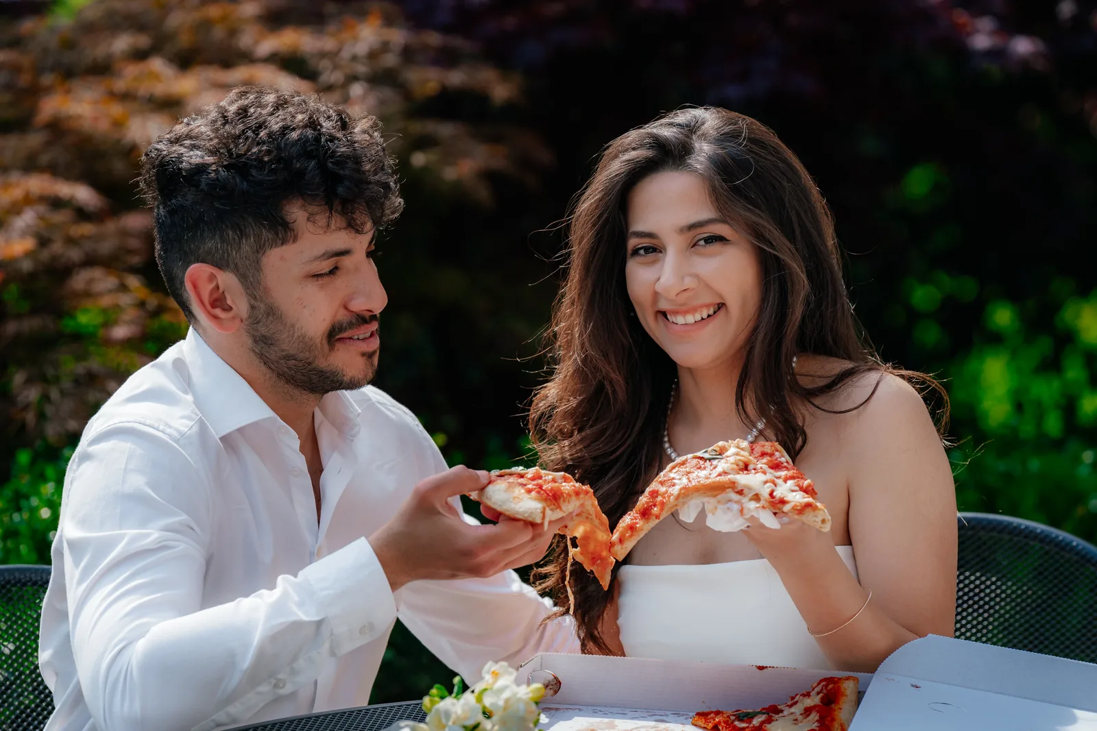 Musa and Solmaz sharing pizza at an outdoor table during their engagement session on Lake Como