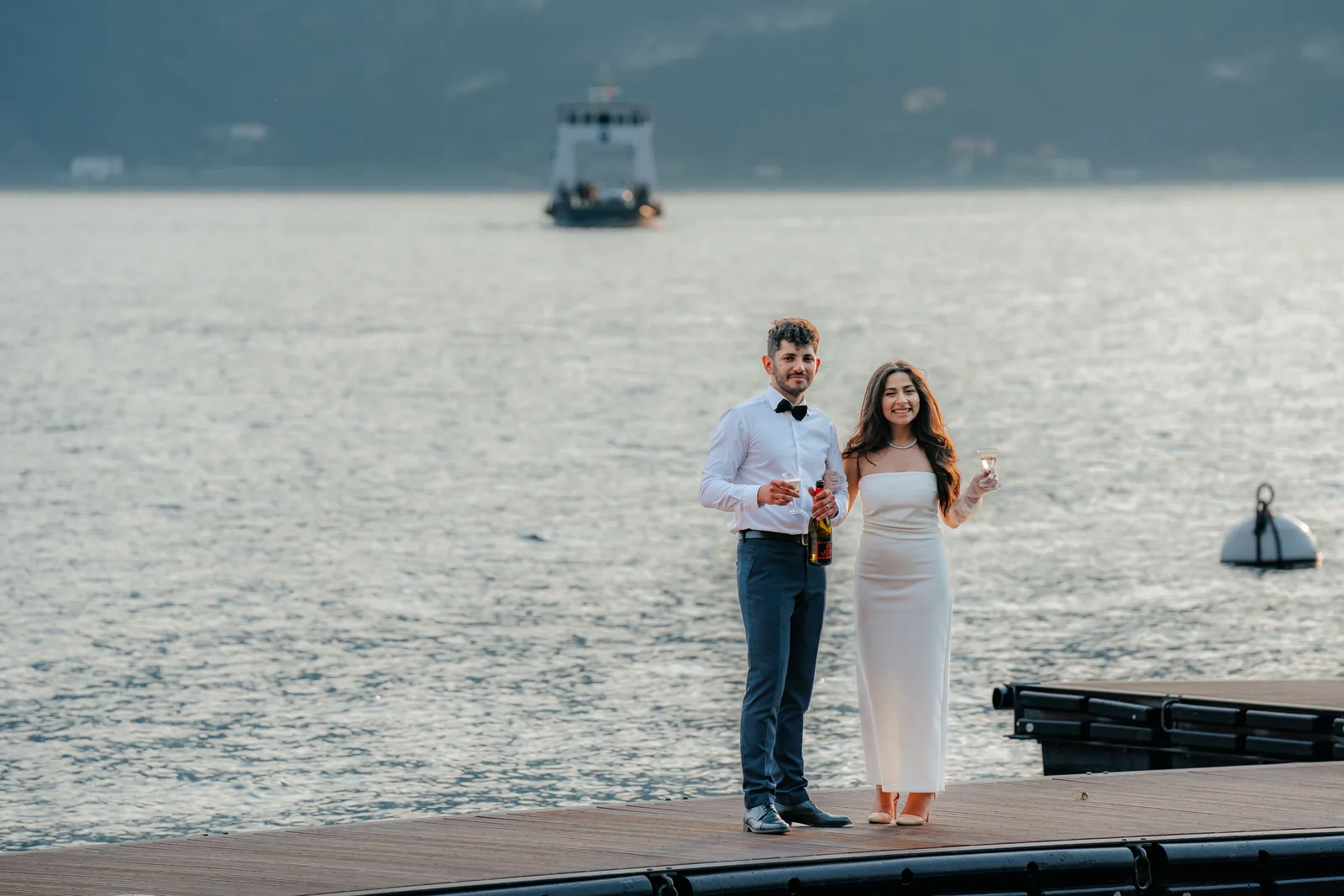 Una coppia brinda su un pontile galleggiante al tramonto, altrove sul Lago di Como (non a Villa Erba)