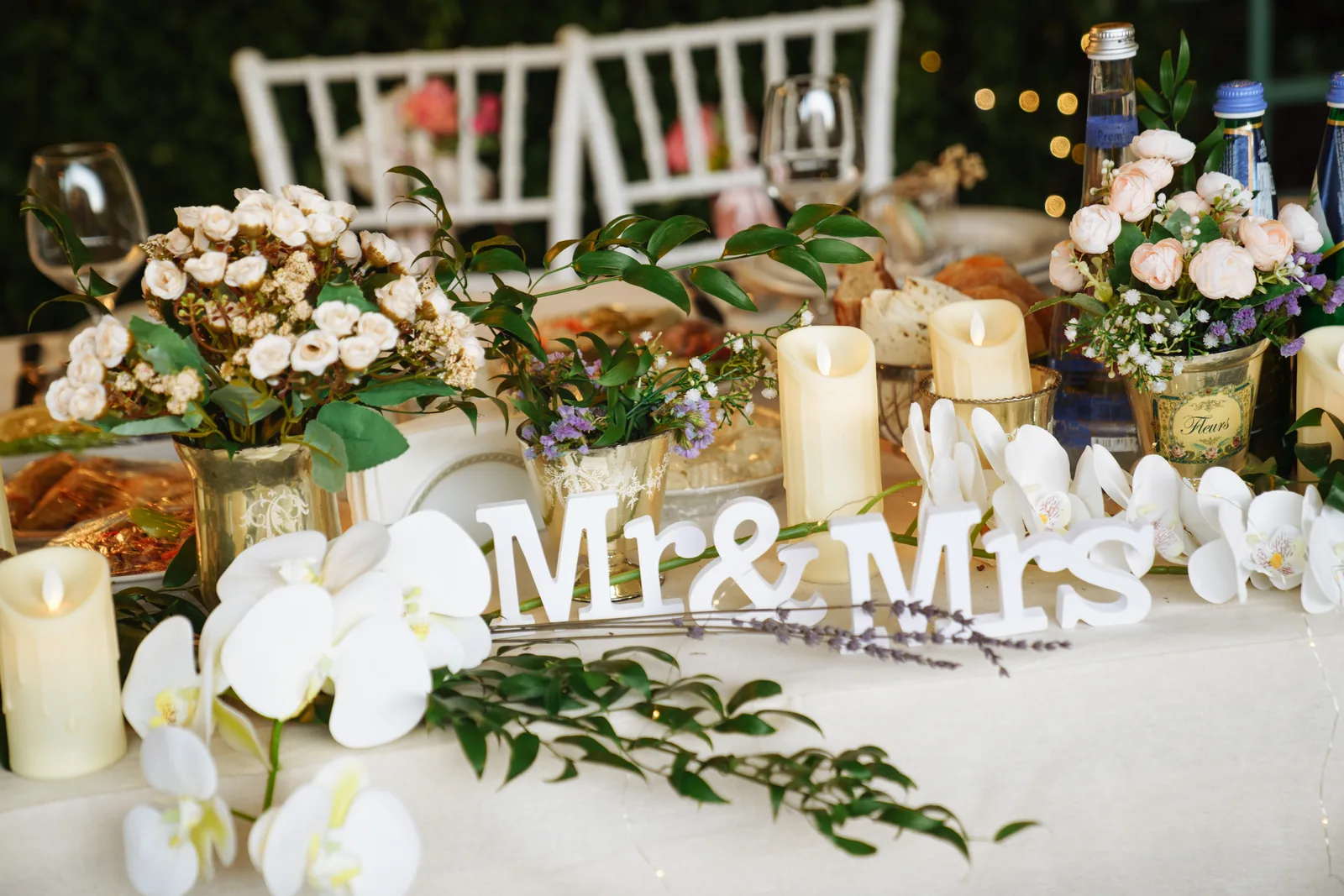 White Mr and Mrs letters among orchids and candles on a wedding head table