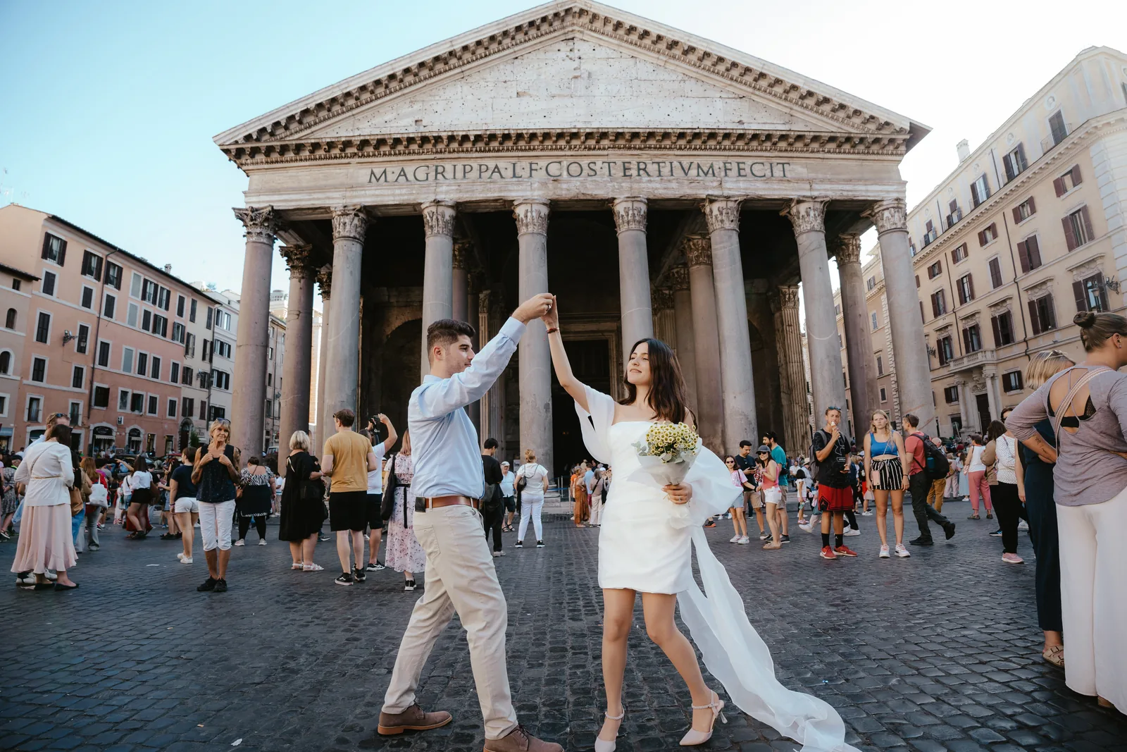 A couple dancing hand in hand on the cobblestones in front of the Pantheon in Rome