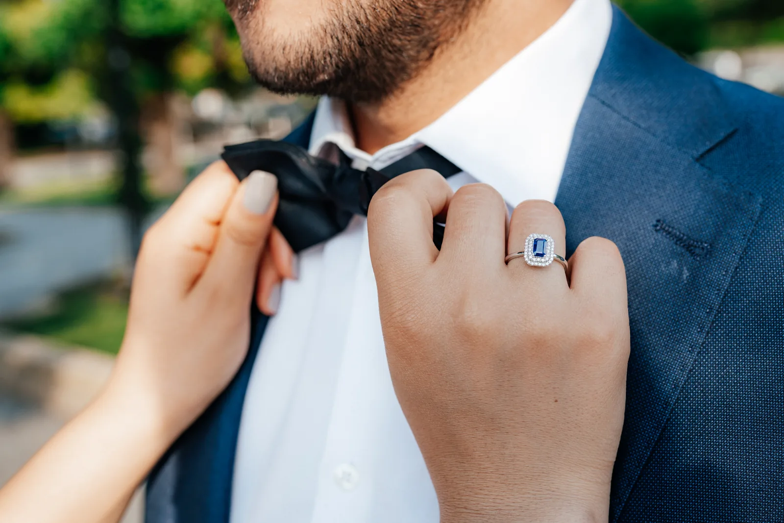 A sapphire and diamond engagement ring beside a bow tie, photographed on Lake Como (not at Villa Cetinale)