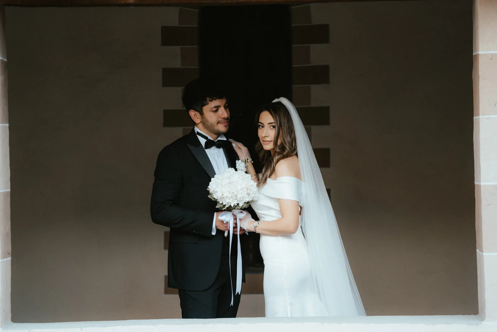 Musa e Solmaz incorniciati da una profonda apertura in pietra durante il loro servizio pre-matrimonio a Susa, in Piemonte (non a Stupinigi)