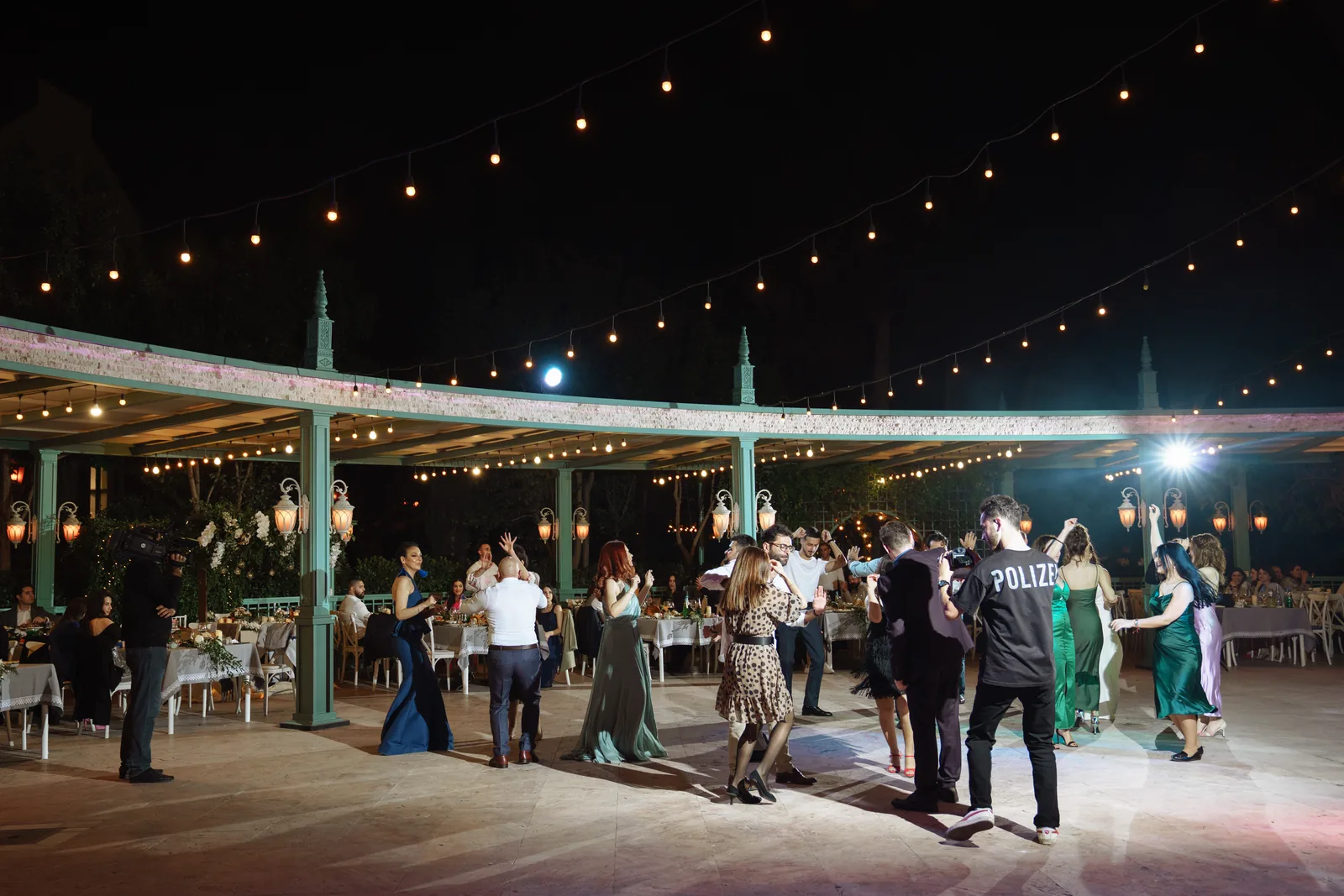 Guests dancing at night on an open-air terrace under festoon lights