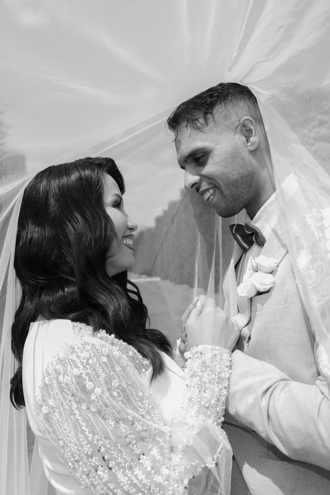 Mohammed and Hejrat smiling at each other under her sheer veil, their hands clasped between them, in black and white