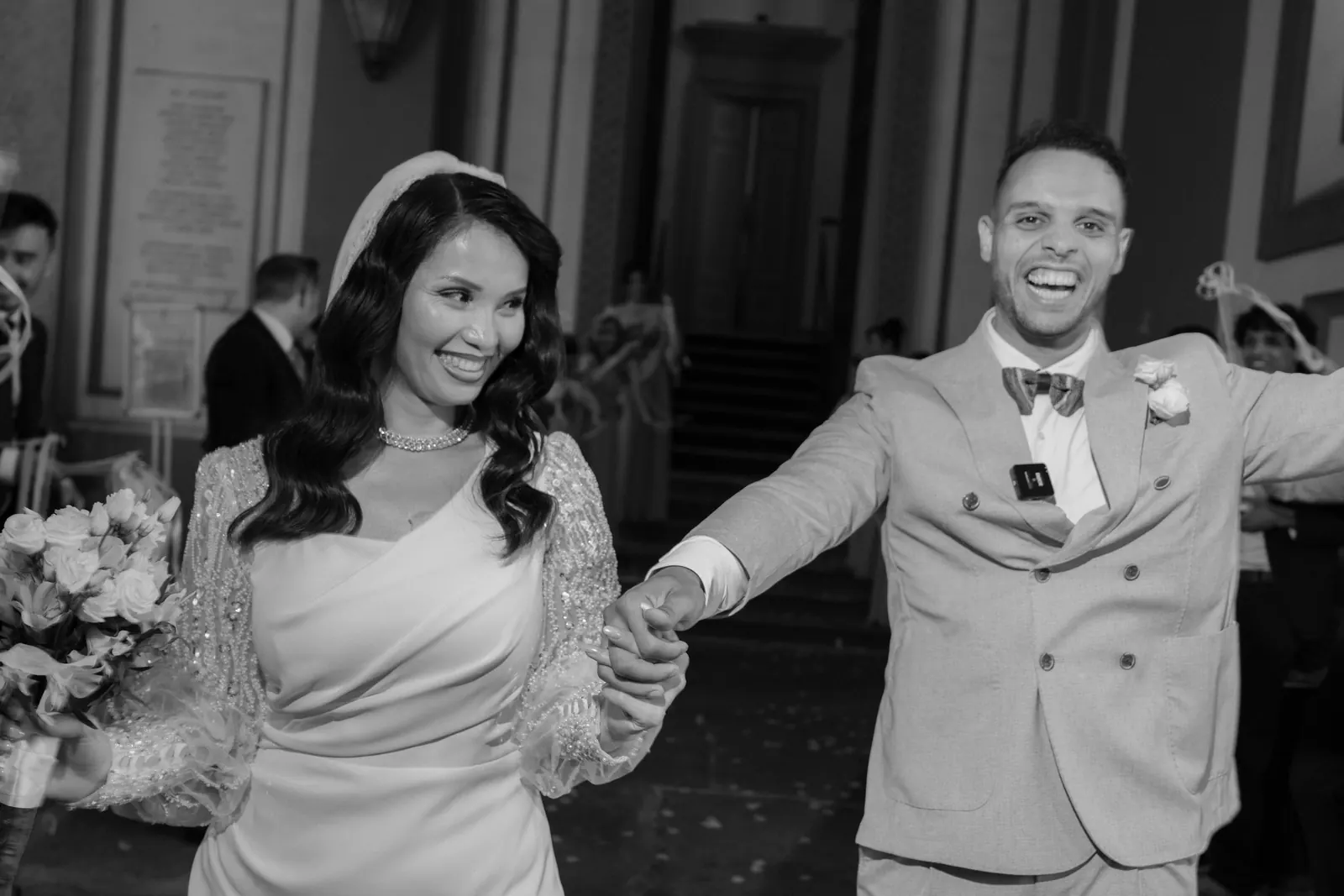 Mohammed and Hejrat walking out of the town hall hand in hand, both laughing, guests behind them